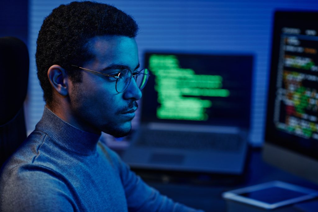 Young serious IT support engineer in eyeglasses looking at computer screen